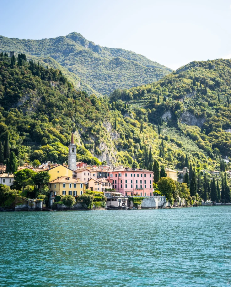 A lake with buildings and mountains at the back.