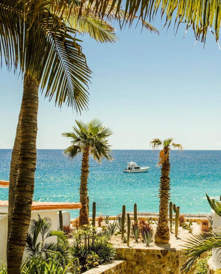 View of the beach and ocean with a small white boat from the resort grounds