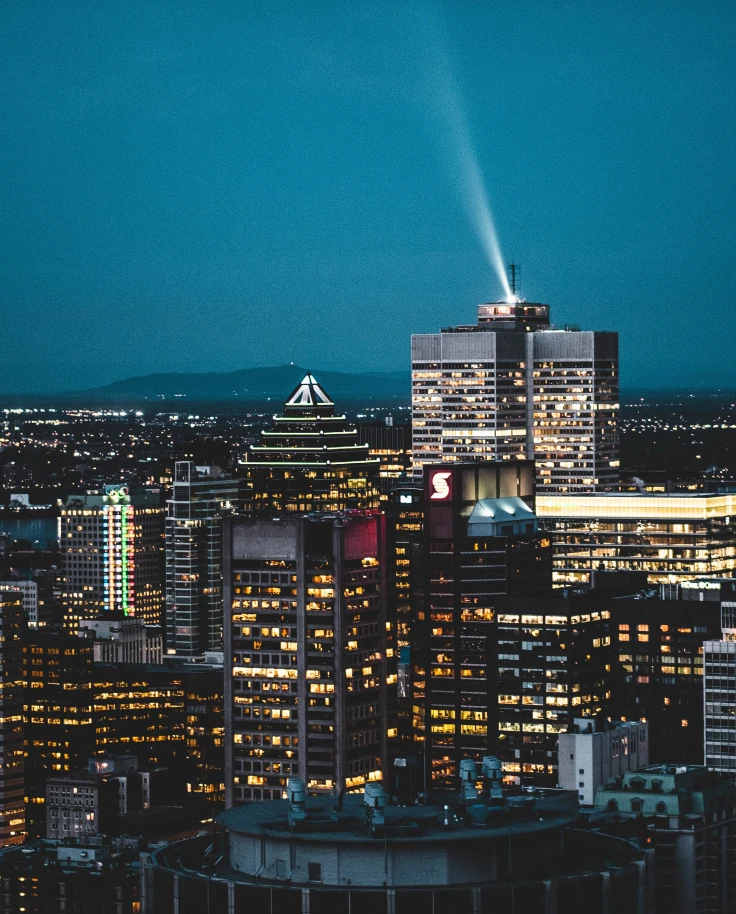 a city view of Montreal at night with dark blue skies and shiny tall gray buildings with yellow lights