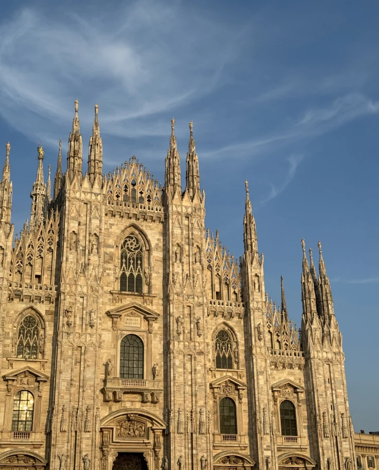 A white gothic church opening up to square at Duomo Cathedral Square in Milan, Italy.