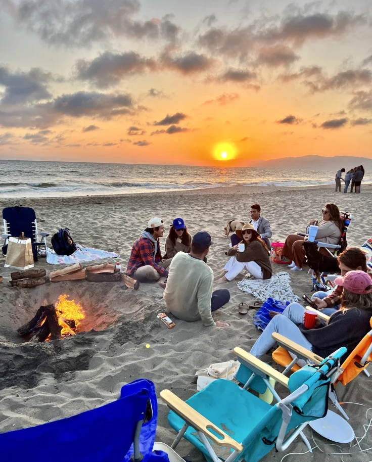People sitting on beach at sunset.