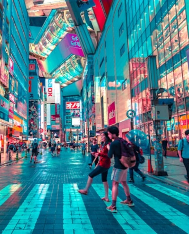 people walking on road near skyscrapers covered in neon billboards.