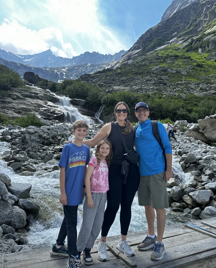 A family of four — two adults and two children — on the rocky slopes of a mountain.