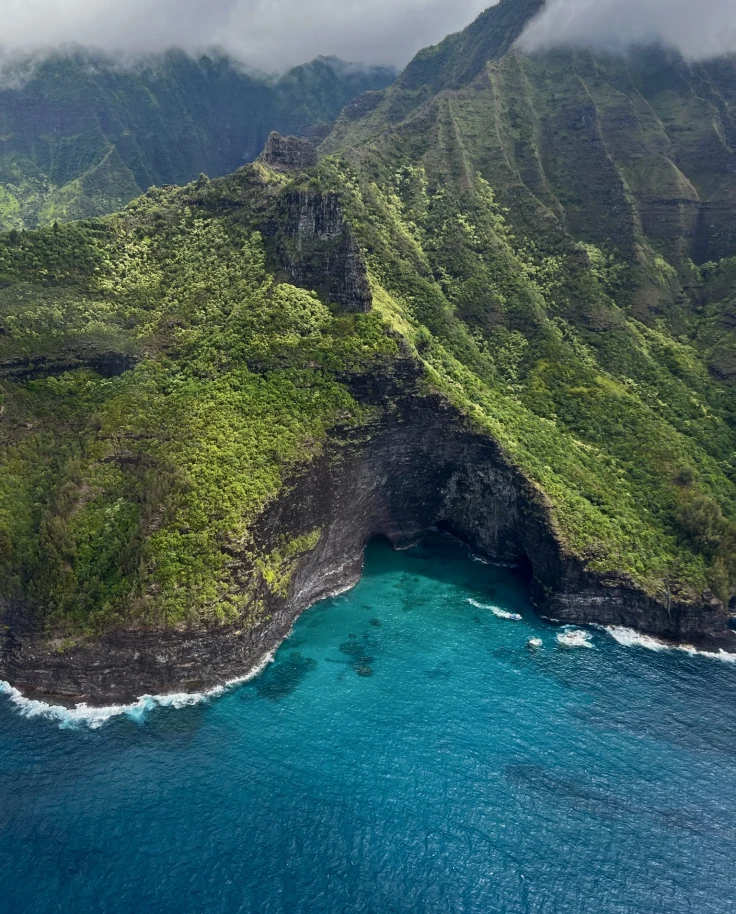 aerial view of green mountain next to body of water
