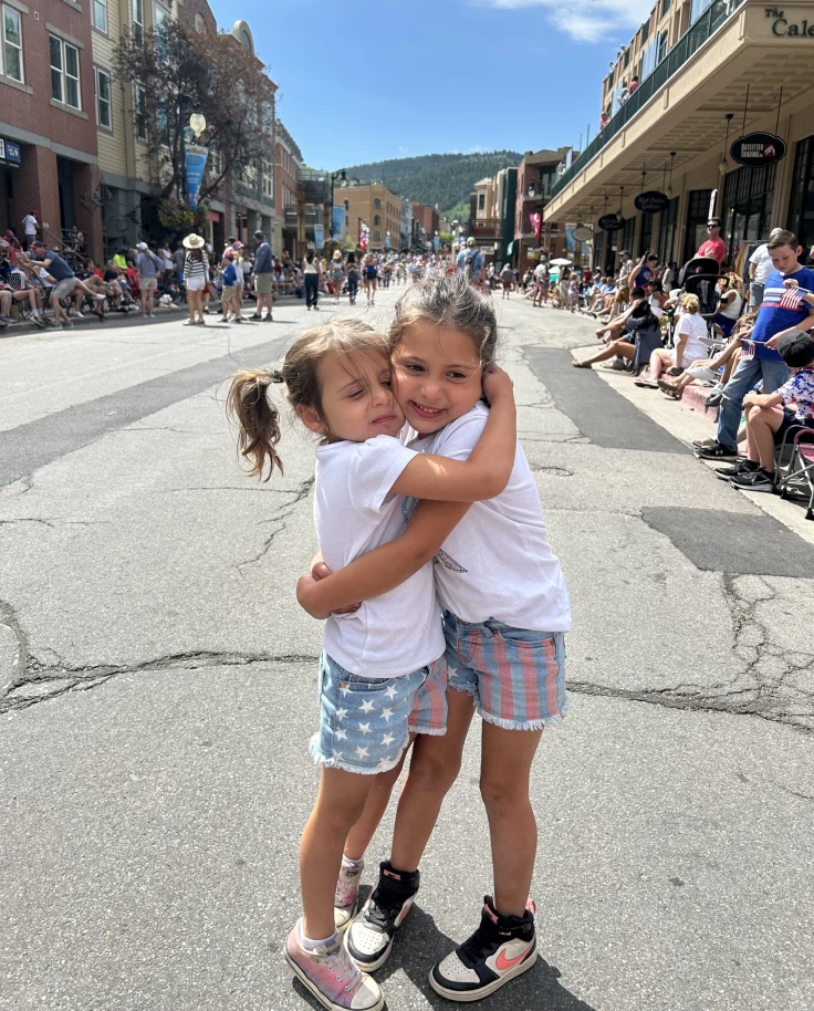 Two kids hugging each other on  a street.