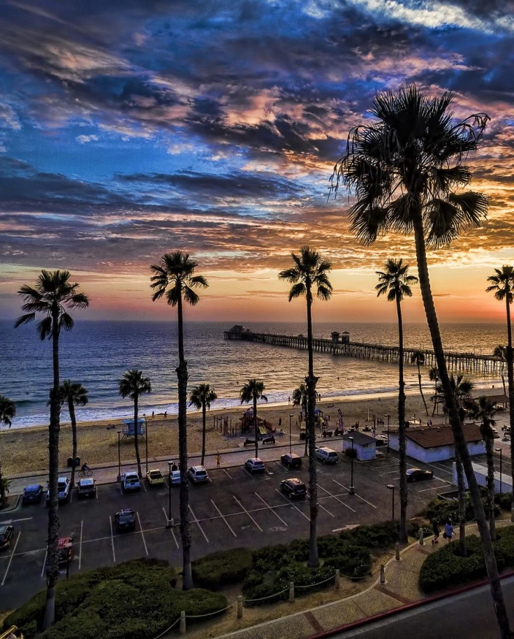 A beautiful view of Oceanside beach with palm trees and a jaw dropping sunset.