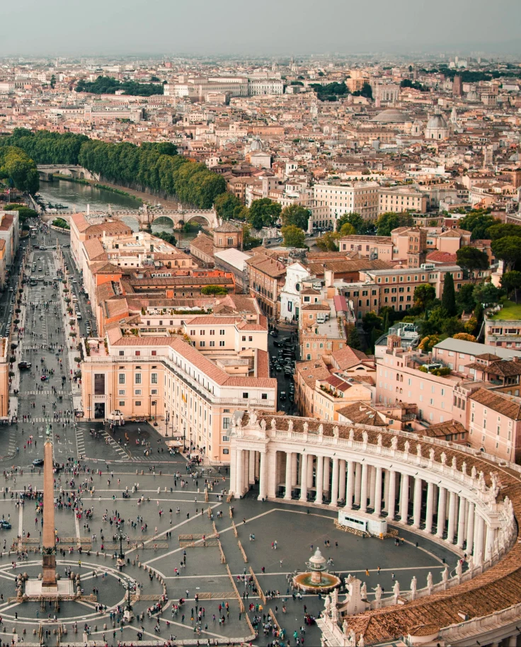 An aerial view of Northern Italy with tan buildings, green trees and a city center.