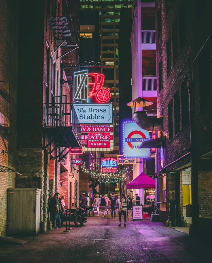 Bright signs with people walking on sidewalk at night