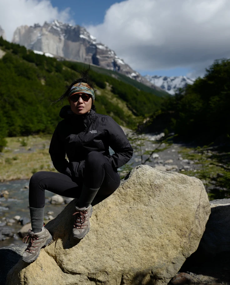 Patagonia person sitting on a rock.