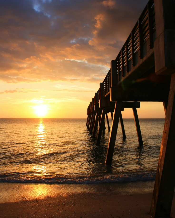 A pier out over the water at sunset.