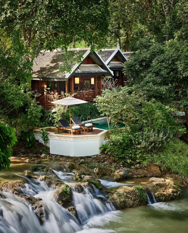 A water fall in a river next to a hotel building