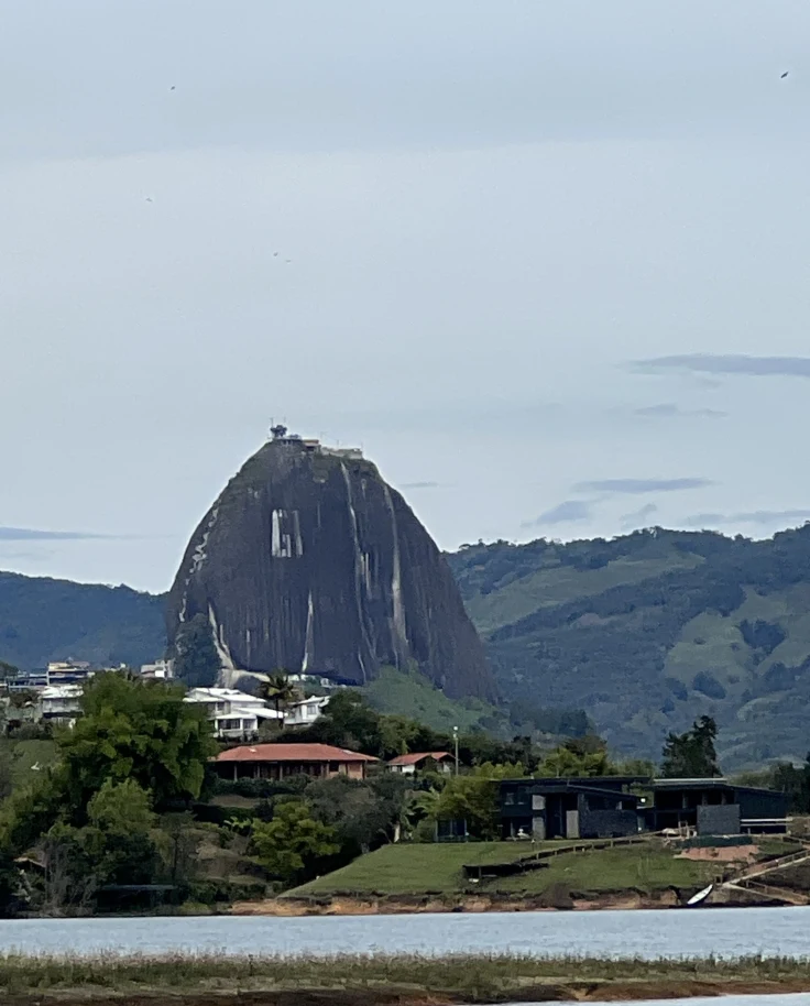 A view of green mountains and a pointed hill with buildings in the foreground.