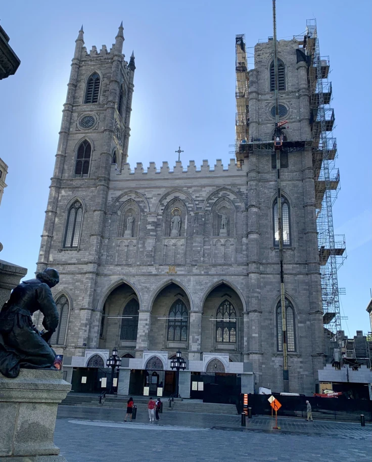 The exterior of the Montreal Notre Dame in the morning with a few people outside