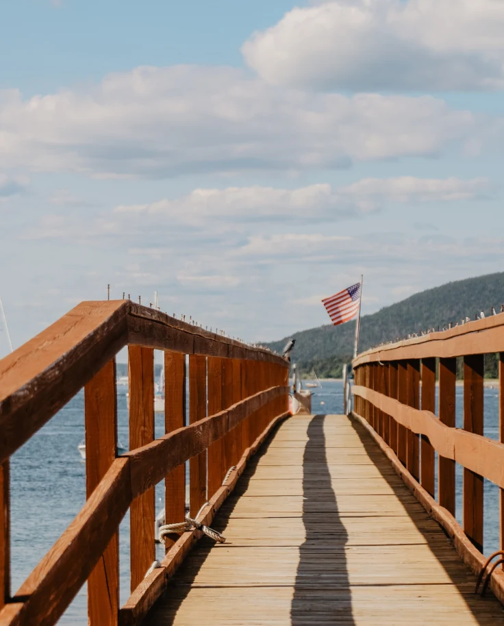 Dock with railing near boats during day.