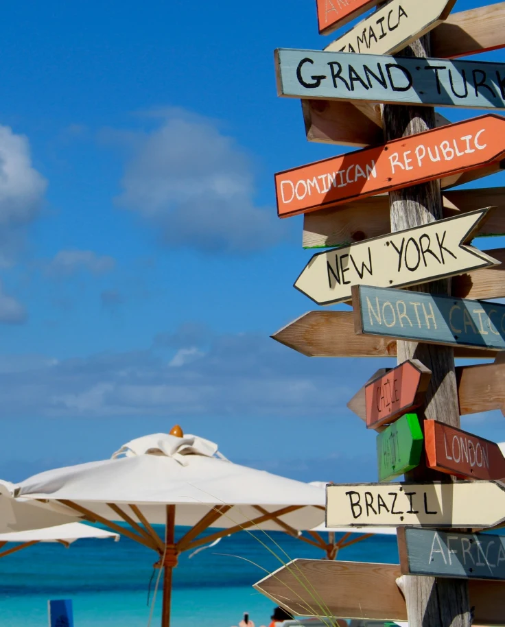 Beach with umbrellas and sign board.