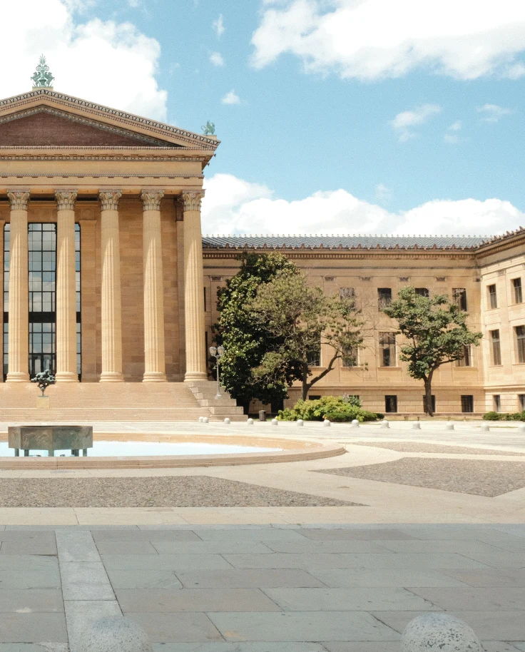 Philadelphia tan building with mountain and a fountain in front blue sky with white clouds