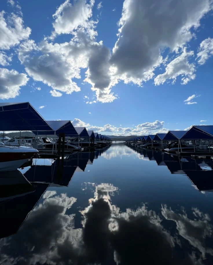 a body of water surrounded by boats under a cloudy blue sky