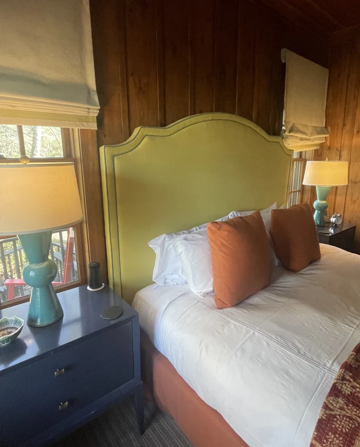 A comfy bed stacked with pillows in a well-lit room at High Hampton Resort.