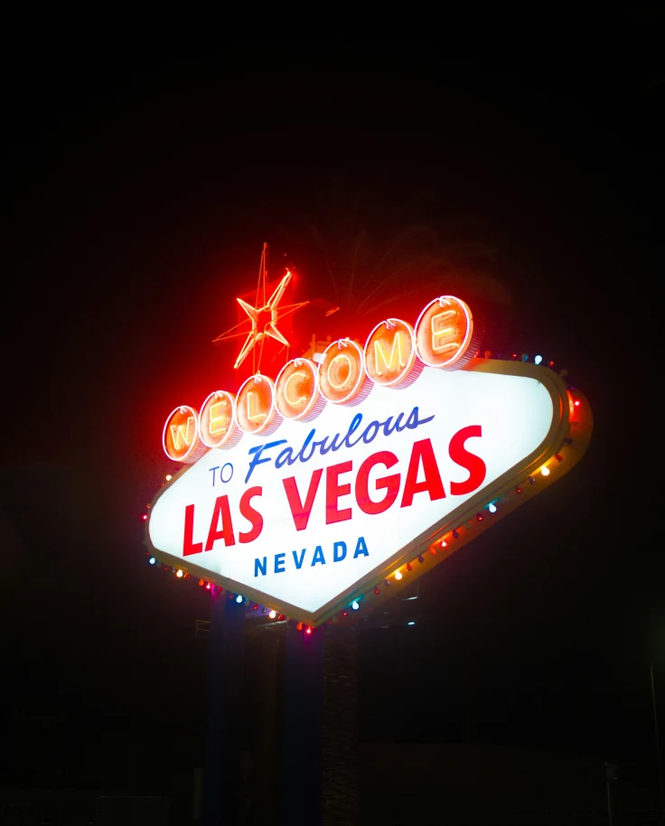 The image shows the iconic “Welcome to Fabulous Las Vegas Nevada” sign illuminated at night.