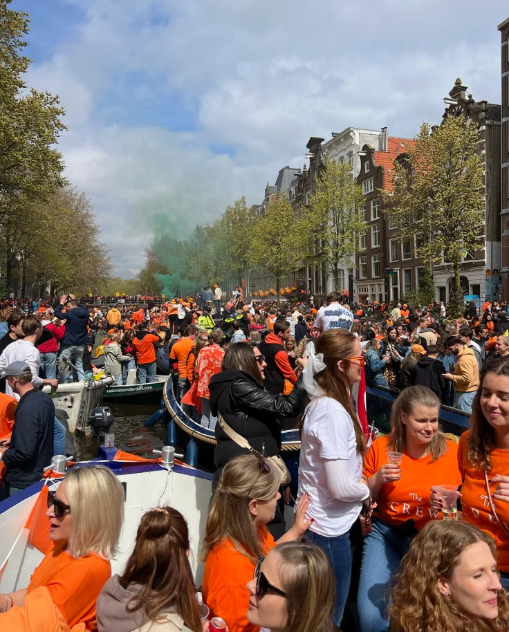 A canal full of boats and large groups of people during the daytime