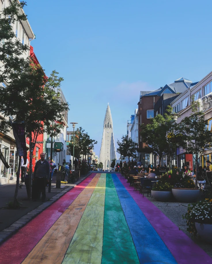 A vibrant pedestrian street with a colorful rainbow path leads towards a distinctive church in the background.