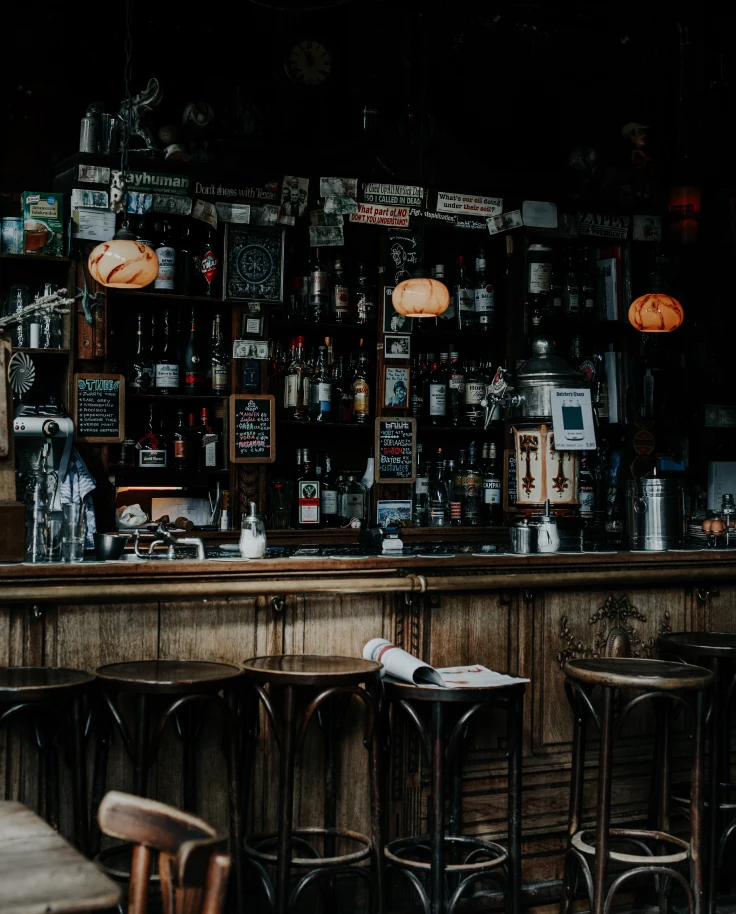 A dark-lit bar with wooden stools in Amsterdam.