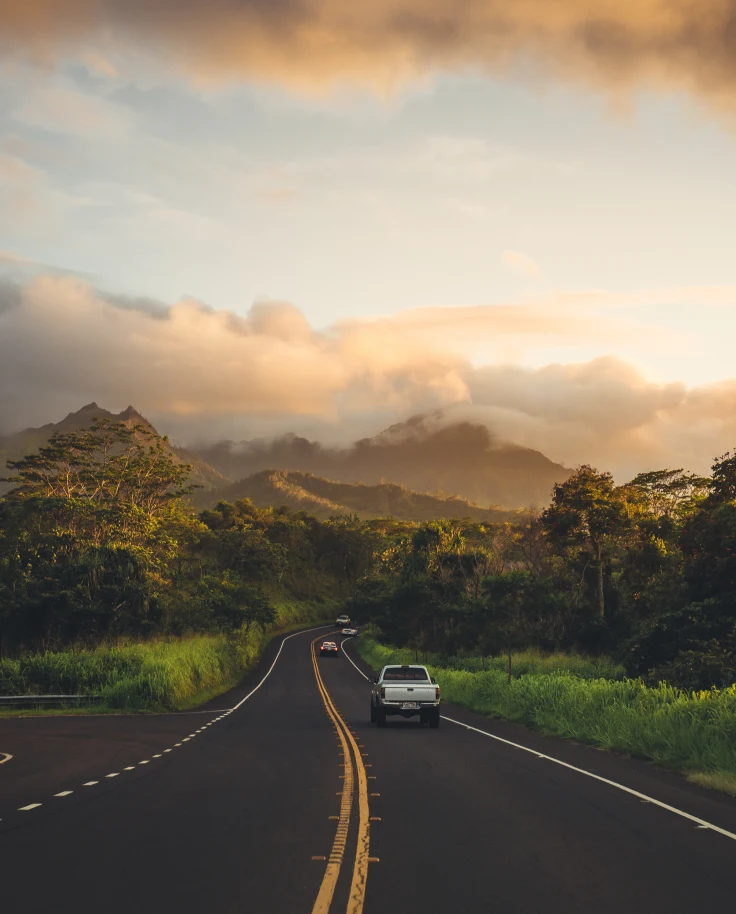 A highway in Hawaii framed by mountains and clouds.