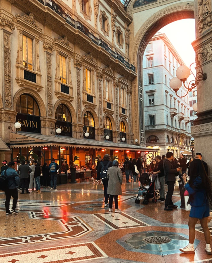 A picture of the interior of a European building with people walking around.