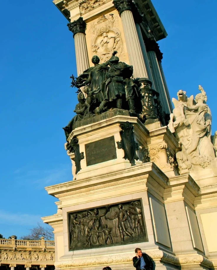A detailed monument with sculptures and bas-reliefs under a clear blue sky.