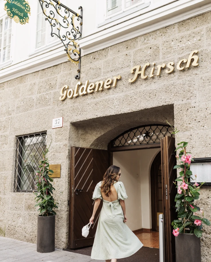 Merissa posing in a green dress in front of a stone storefront outside.