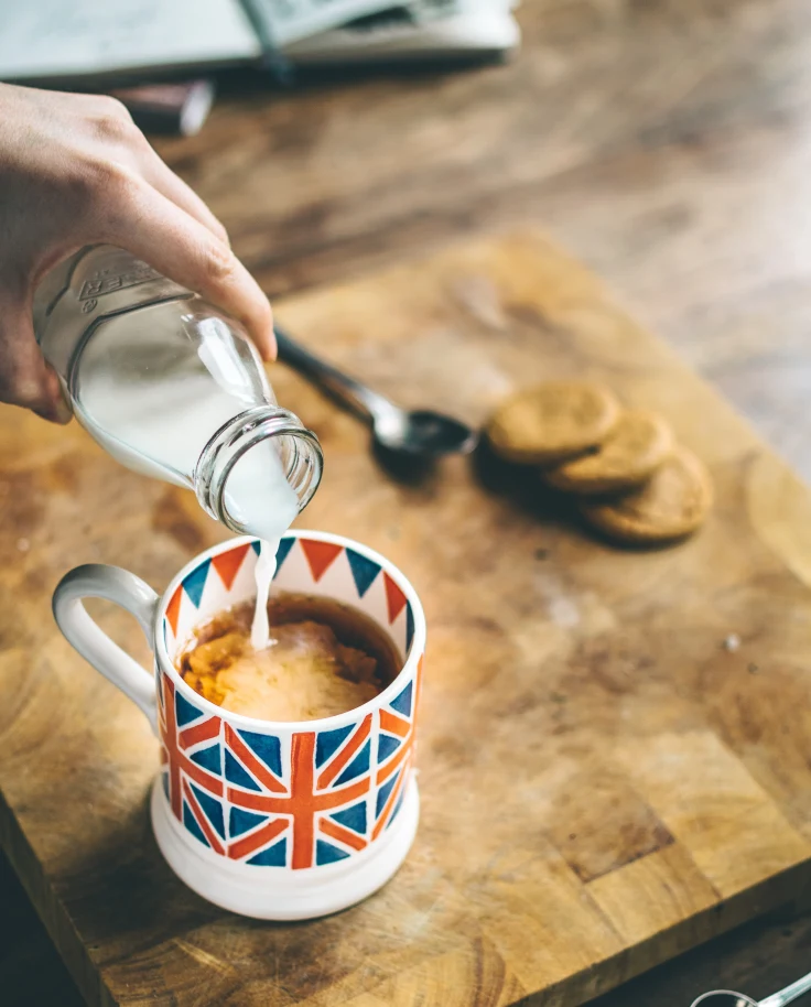 A cup with the British flag on it with black tea and milk.