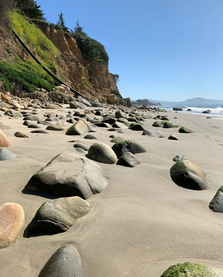 A sandy beach with large rocks scattered around