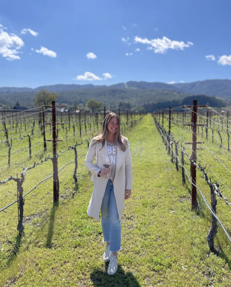 A woman posing in a vineyard during day time.