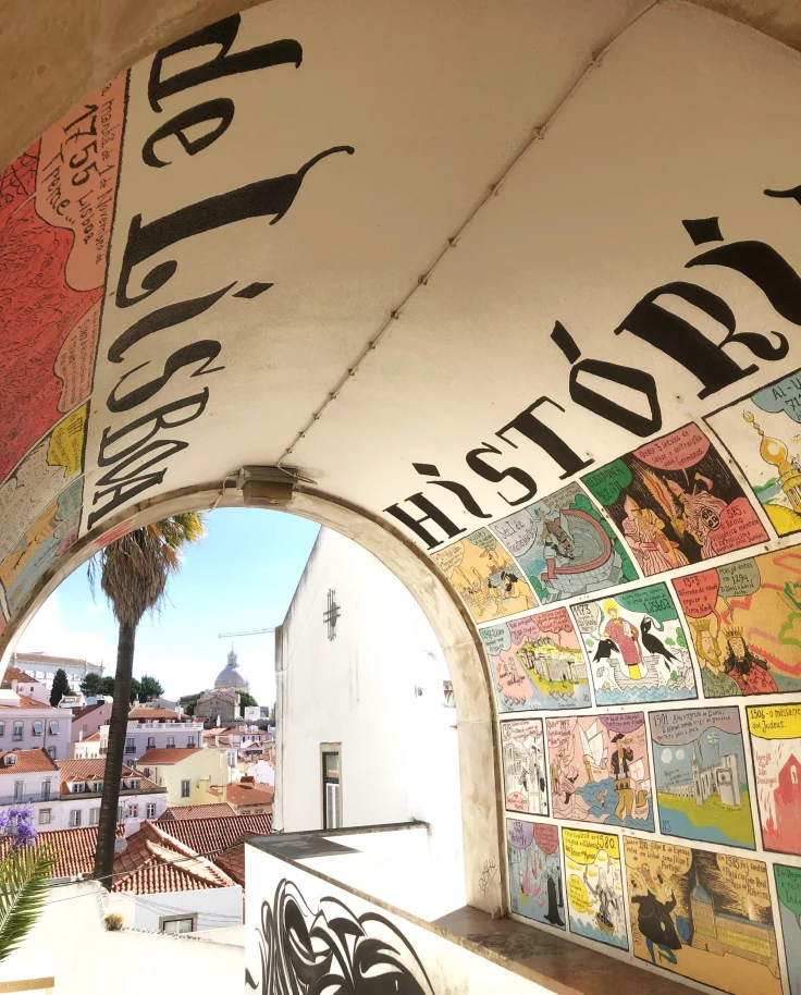 A vibrant mural under an archway with the word “History,” overlooking a sunny cityscape.