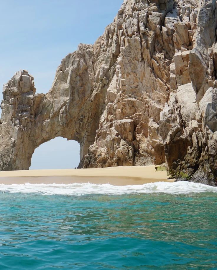 beachside cliffs with blue water and tan san in los cabos mexico