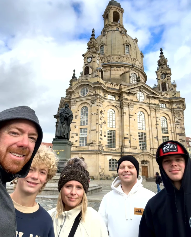 A family posing in front of architectural buildings during daytime.