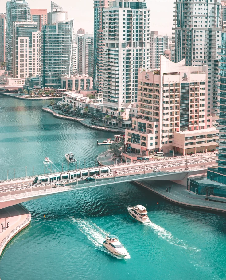 View of boats passing under bridge with buildings in the background in Dubai