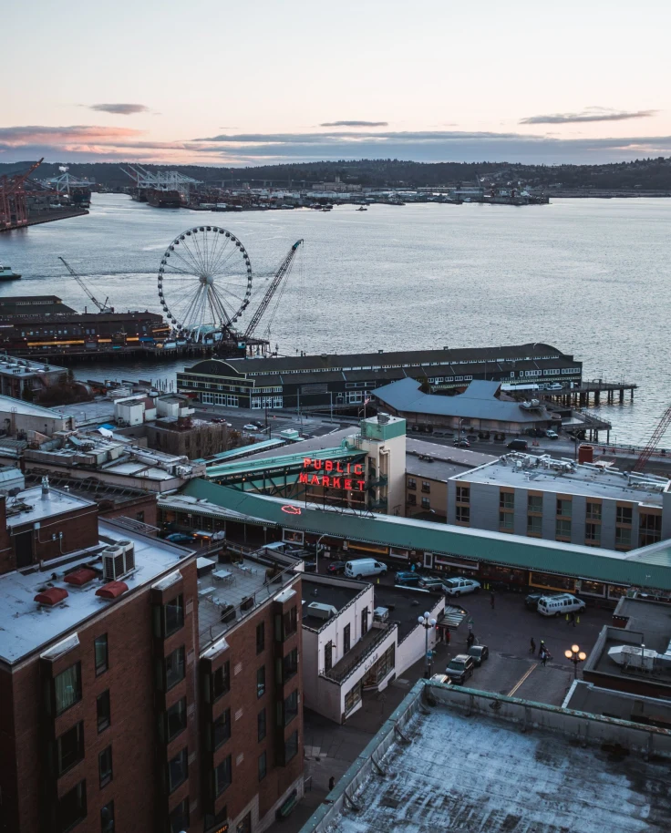 a winter city on the water at sunrise with a ferris wheel