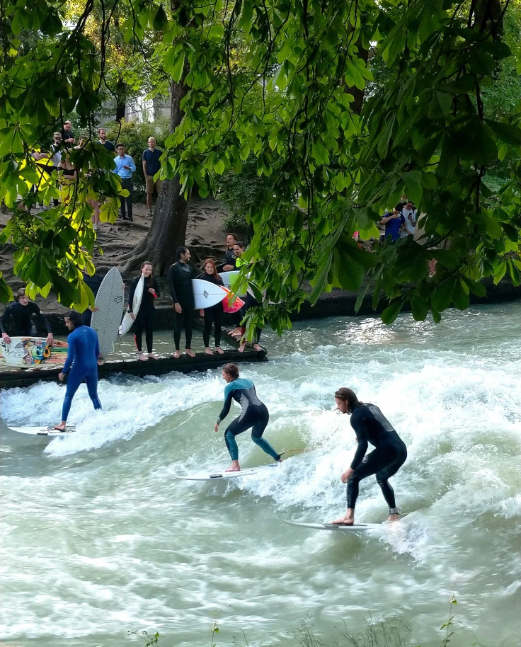 A picture of three people surfing in the water during the daytime.