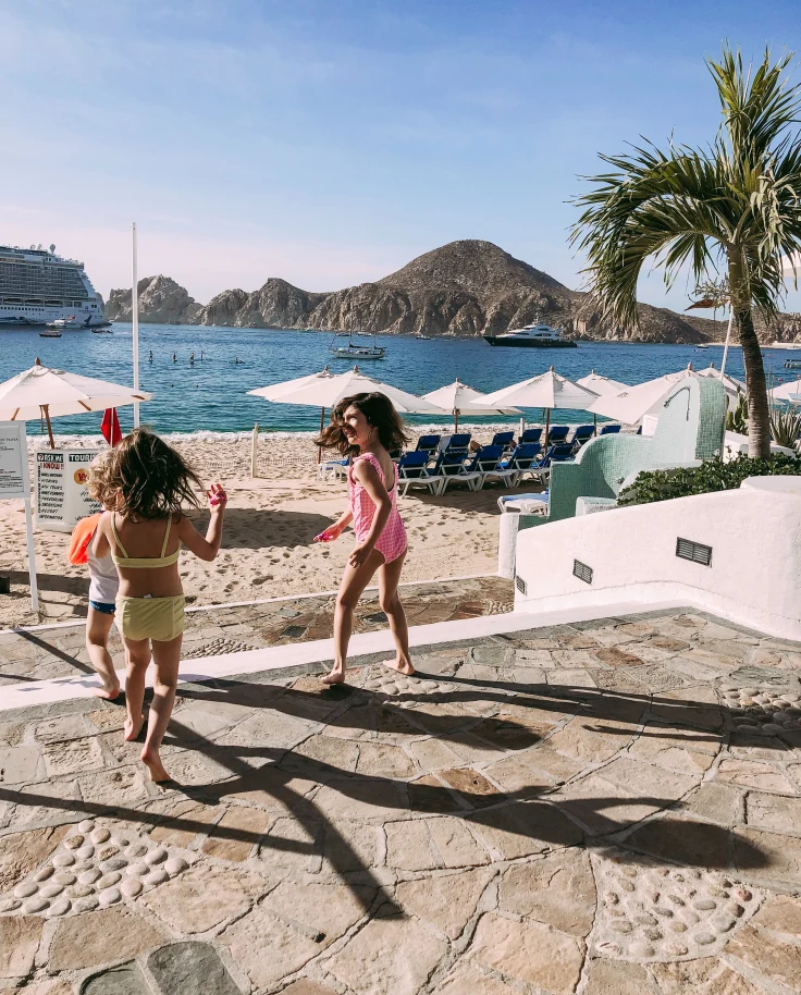 children standing on pool deck with mountain in background