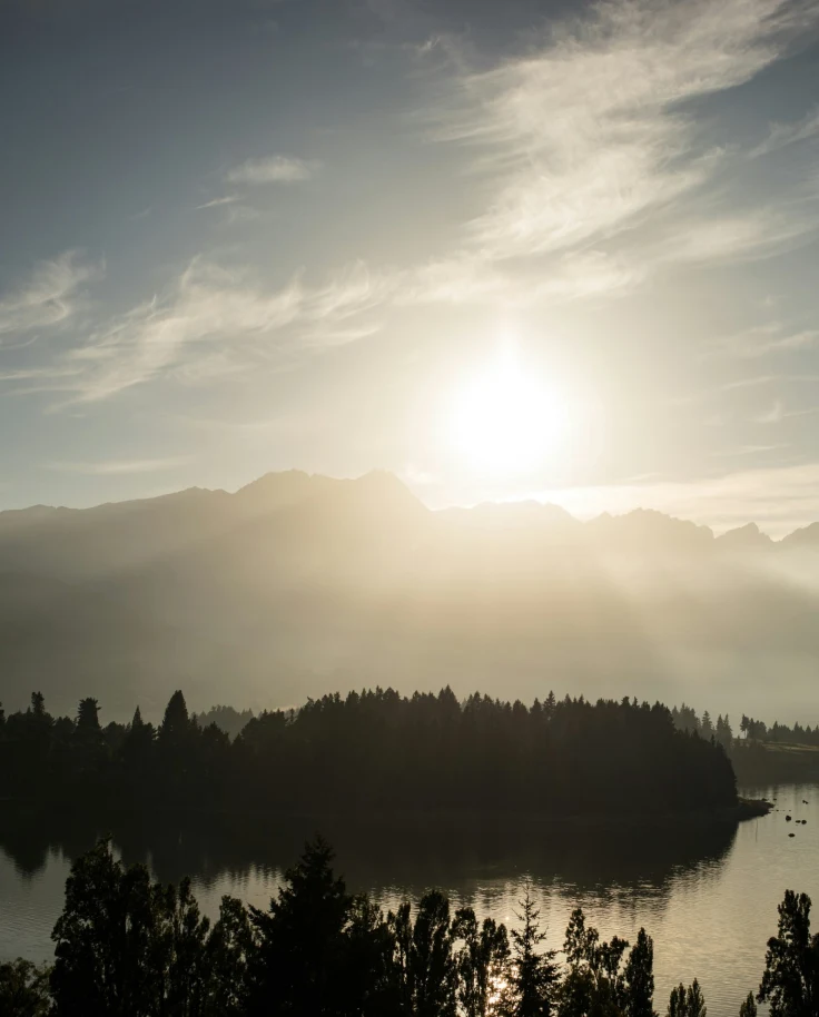 The sun's rays glide over dense foliage and clear waters and wisps of clouds drift overhead.