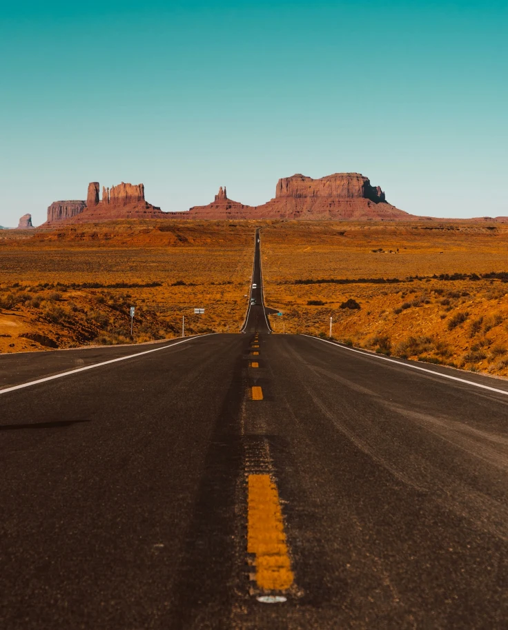 A road leading towards red rock formations.