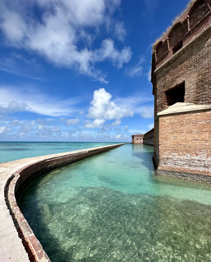 A picture of water near a brown concrete building taken during daytime.