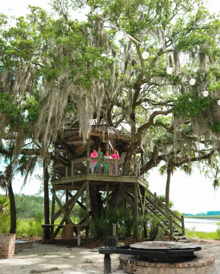 family stands in a treehouse in the forest in Palmetto.