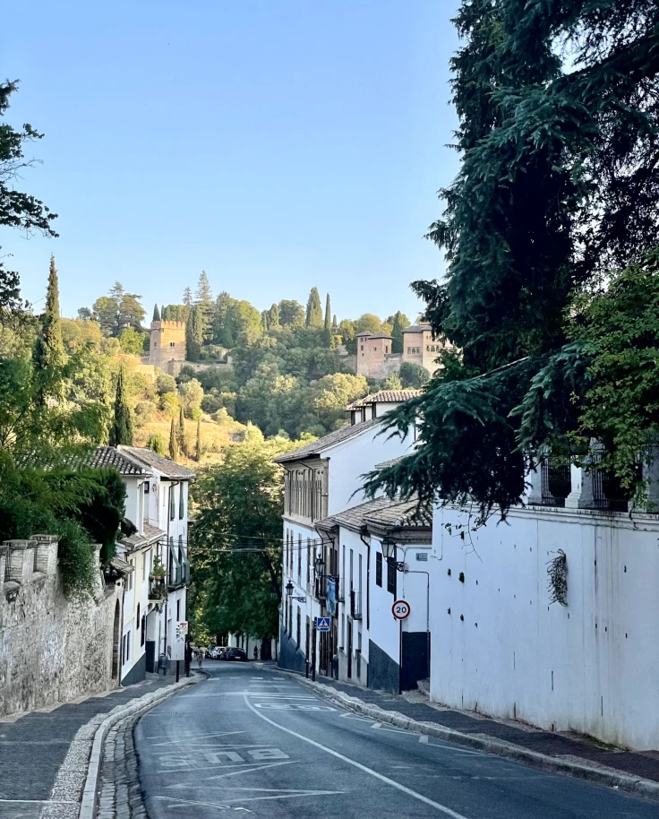 A serene street view with traditional white buildings under a clear blue sky, possibly in a historic European town.