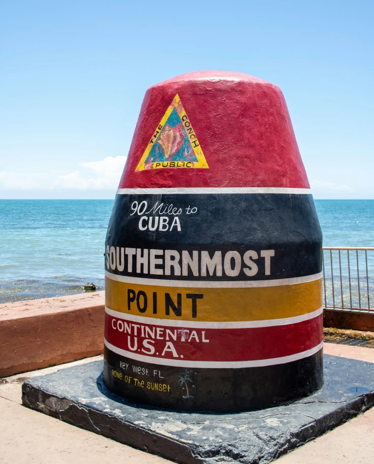 A colorful landmark next to a body of water reading "Southernmost Point, Continental USA"