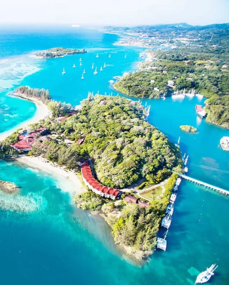 An aerial view of trees and turquoise blue water surrounding an island.