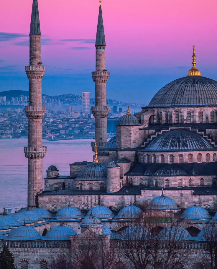 large tower next to body of water with a colorful sunset