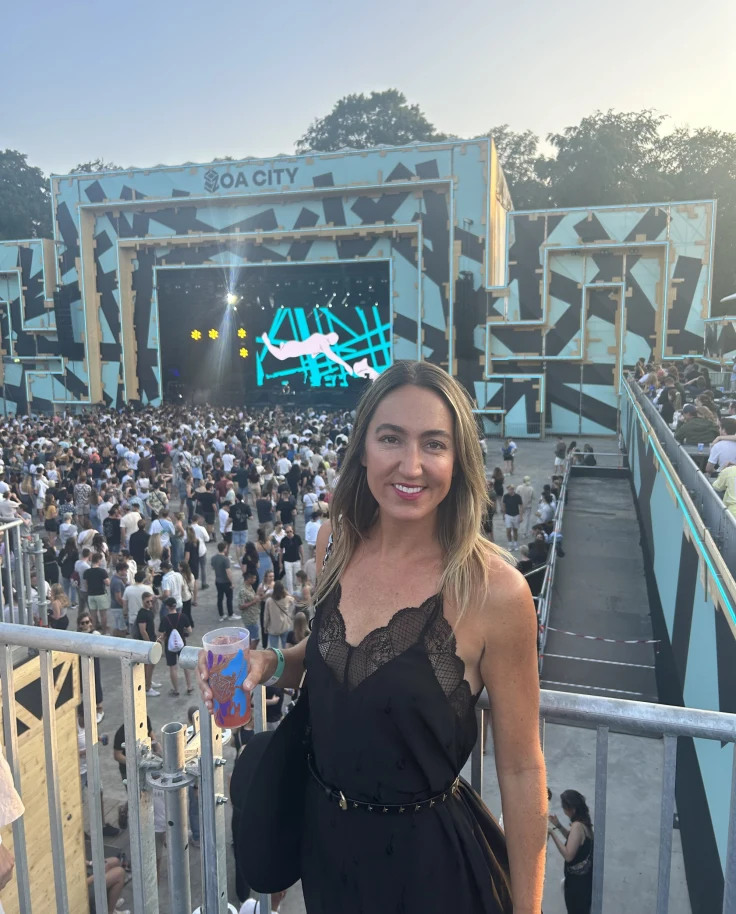 A woman in black dress with a concert crowd at the back.