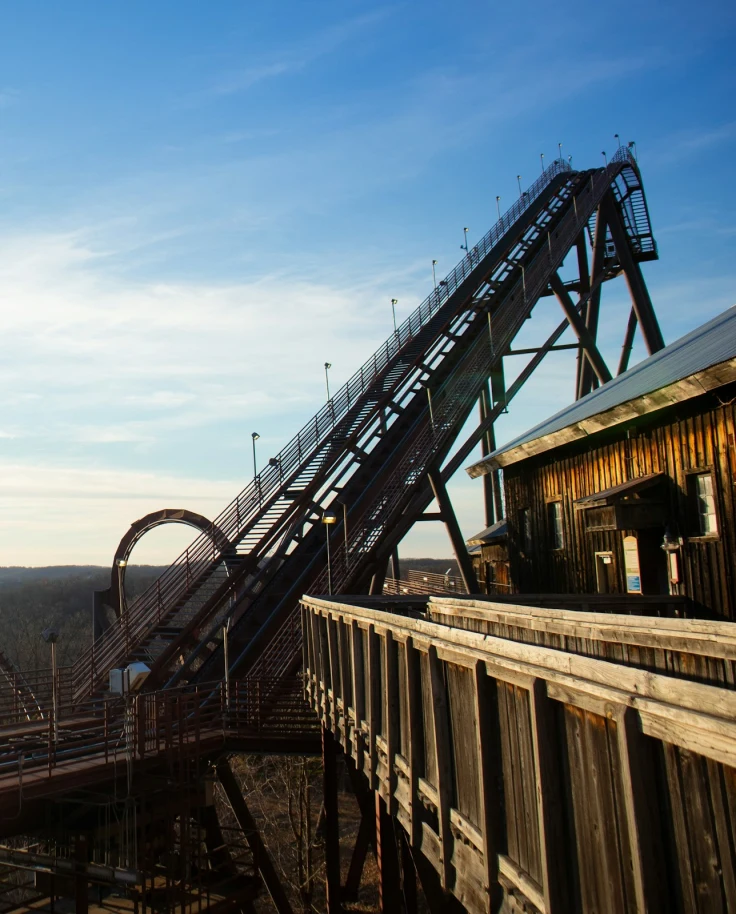 A view of amusement park rides with a vast blue sky in the background. The sun is also shining towards the left of the photo.